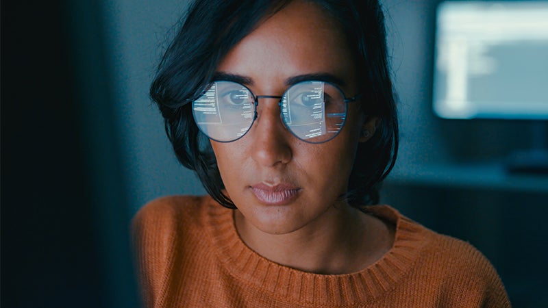 Woman with glasses looking at computer screen.